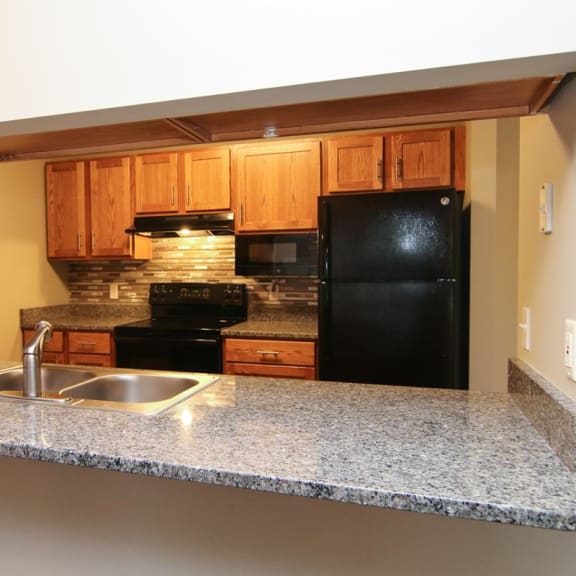 Thumbnail 8 of 27 a kitchen with a granite counter top and a black refrigerator