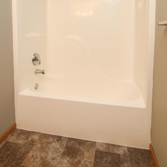 Thumbnail 17 of 27 a white bath tub in a bathroom with an empty curtain rod