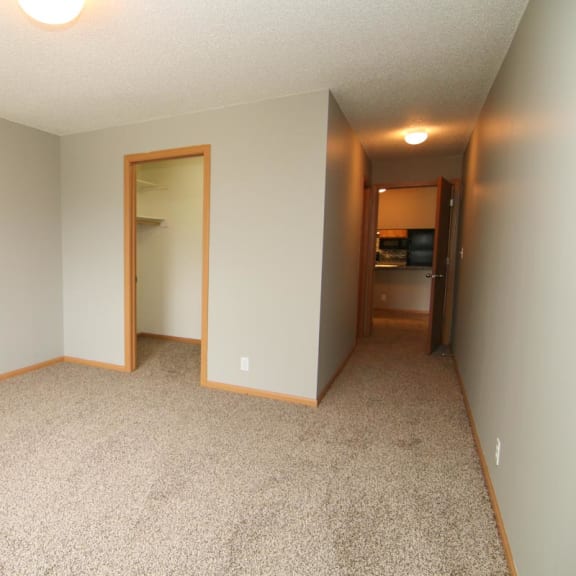 Thumbnail 20 of 27 an empty living room with carpeting and a door to a bedroom