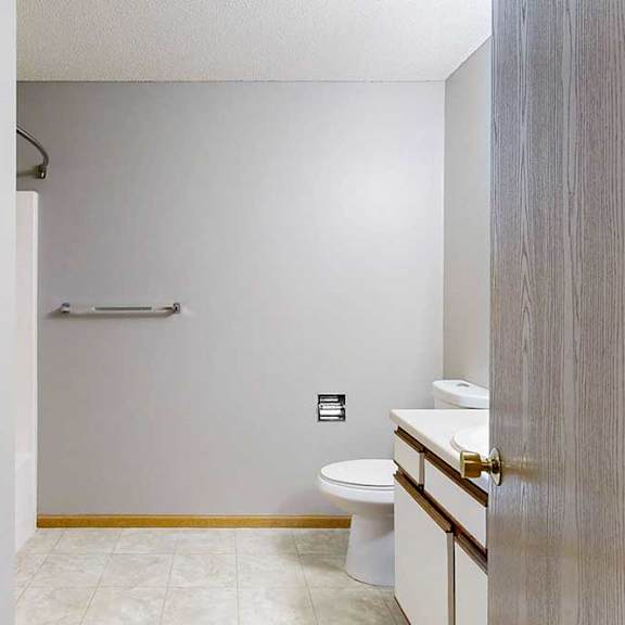 Thumbnail 4 of 29 A bathroom with a toilet, sink, and a towel bar.