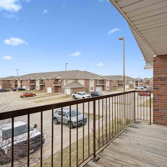Thumbnail 16 of 28 A balcony with a railing overlooking a parking lot and apartment buildings.