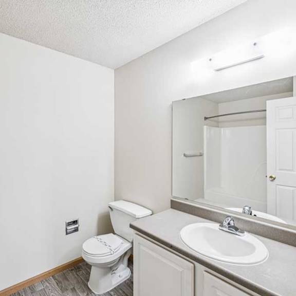 Thumbnail 22 of 28 A white bathroom with a toilet, sink, and mirror.