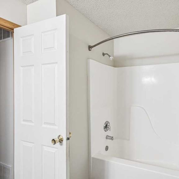 Thumbnail 28 of 28 A white bathroom with a white tub and a white door.