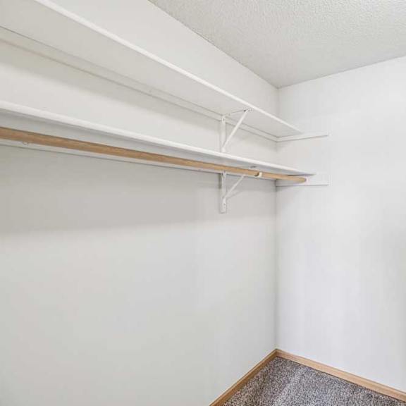 Thumbnail 25 of 28 A white closet with a wooden floor and white walls.