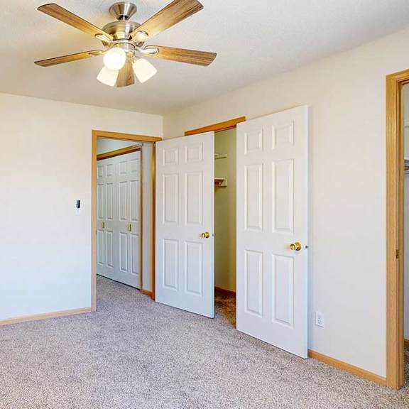 Thumbnail 17 of 31 a carpeted bedroom with ceiling fan and two walk-in closets