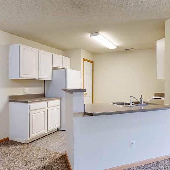 Thumbnail 6 of 31 a kitchen with white cabinets, a peninsula countertop, full-sized appliances, a double basin stainless steel sink, and vinyl flooring