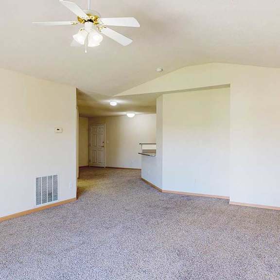Thumbnail 21 of 31 a carpeted living room with open layout, next to a kitchen peninsula