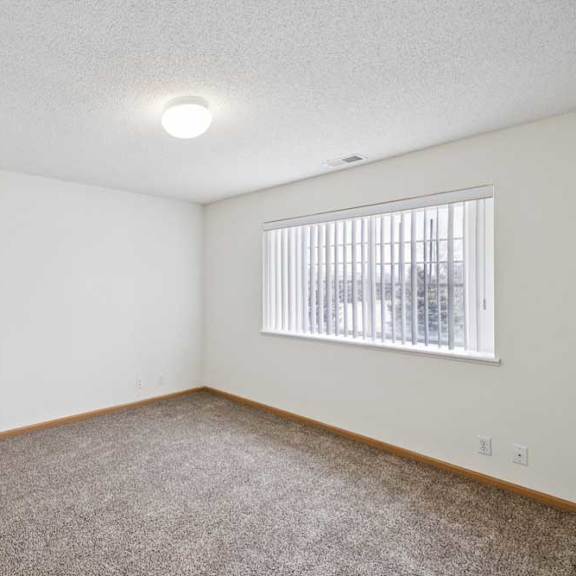 Thumbnail 45 of 61 A room with a carpeted floor and a window with blinds.
