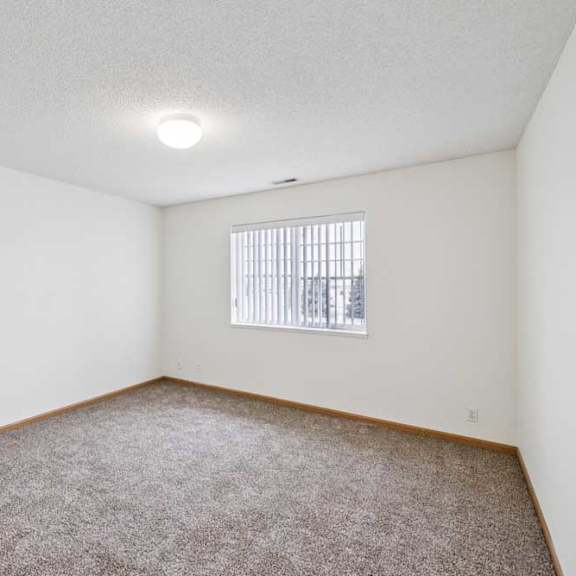 Thumbnail 43 of 61 A room with a carpeted floor and a window with blinds.
