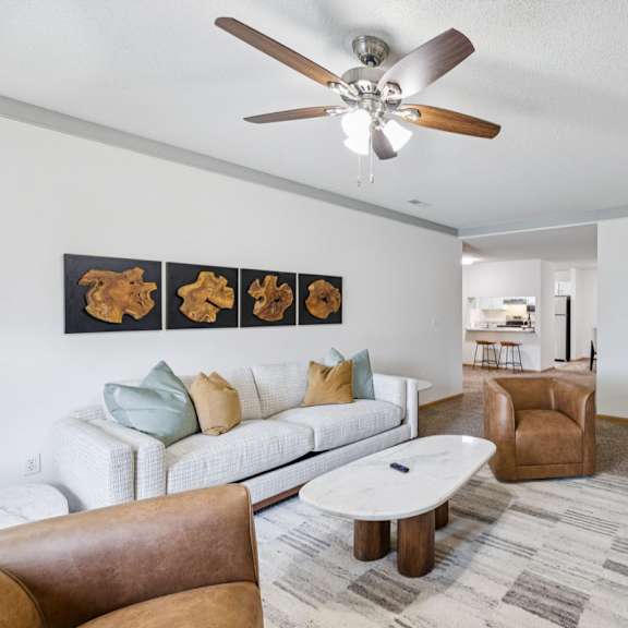 Thumbnail 16 of 56 Apartment living room with a white couch, brown chair, and a ceiling fan.