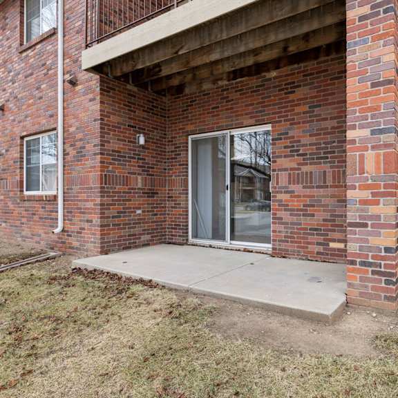 Thumbnail 30 of 56 A brick apartment building with concrete patio and sliding glass door