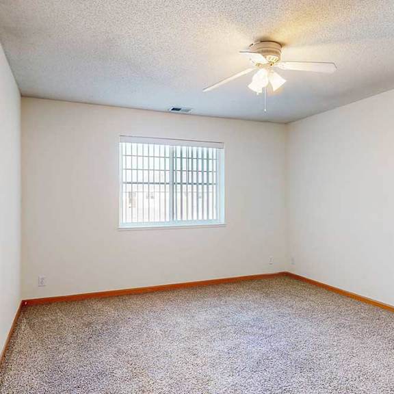 Thumbnail 24 of 29 a carpeted bedroom with a ceiling fan and a large window