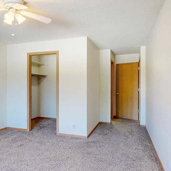Thumbnail 23 of 29 a carpeted bedroom with a walk-in closet, a ceiling fan, and an attached bathroom