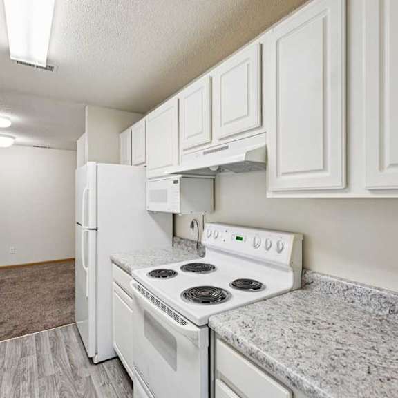 Thumbnail 34 of 48 A white kitchen with a stove top oven and a refrigerator.