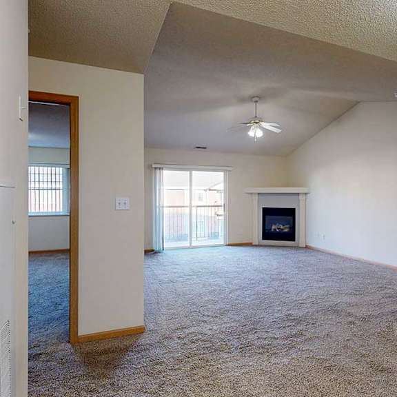 Thumbnail 9 of 28 a spacious living room with a fireplace and a ceiling fan