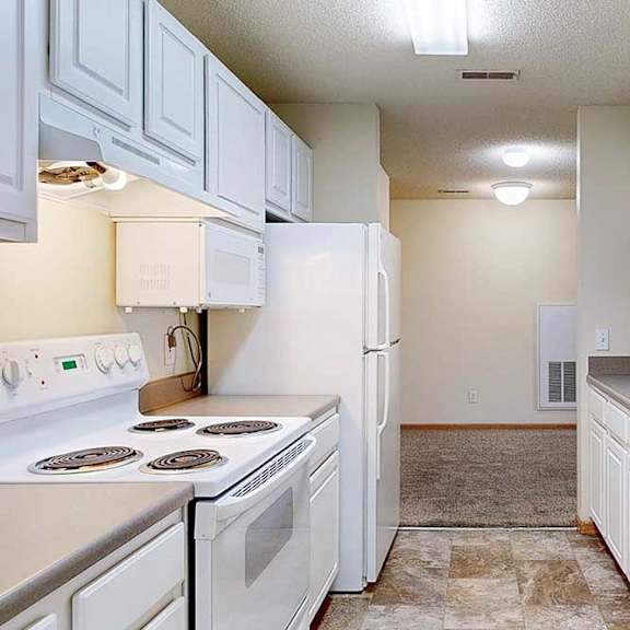 Thumbnail 6 of 28 a galley-style kitchen with white appliances and cabinets