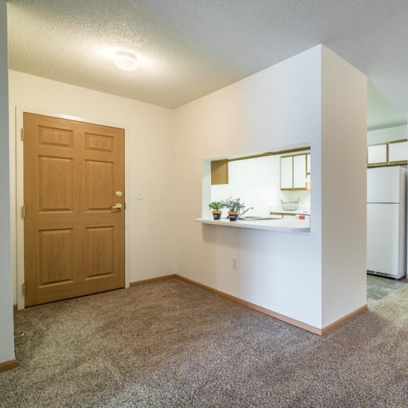 Thumbnail 2 of 17 an empty living room with a refrigerator and a door