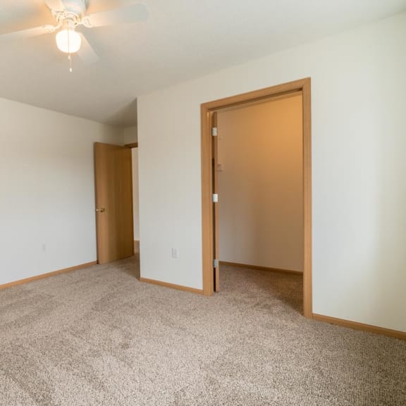 Thumbnail 14 of 17 an empty bedroom with a ceiling fan and a door to a bedroom