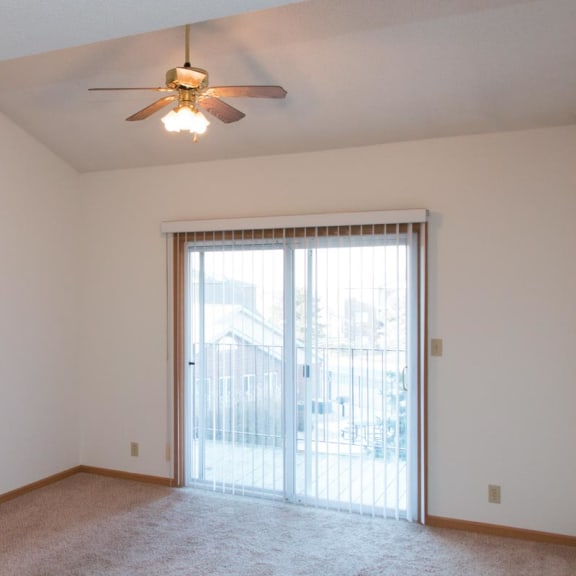 Thumbnail 2 of 16 a living room with a ceiling fan and a door to a balcony