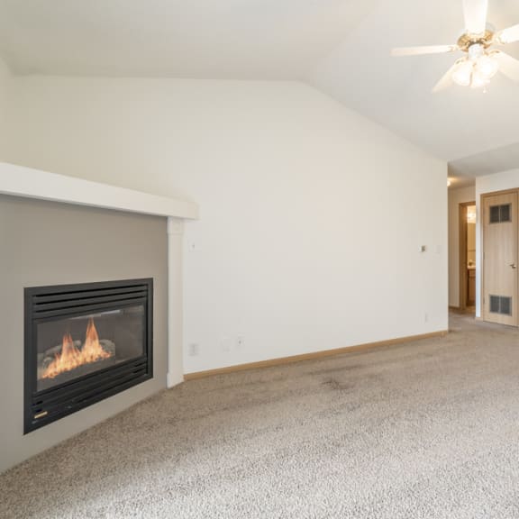 Thumbnail 3 of 11 an empty living room with a fireplace and a kitchen