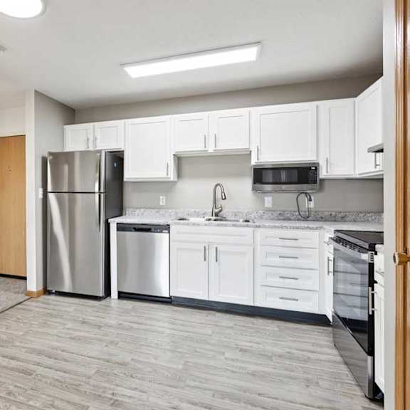 Thumbnail 14 of 22 A kitchen with white cabinets and a grey floor.