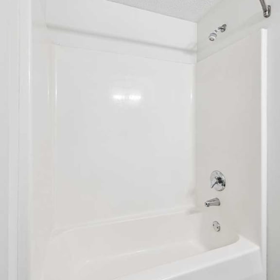 Thumbnail 16 of 18 A bathroom tub shower with chrome fixtures and a curved shower curtain rod.