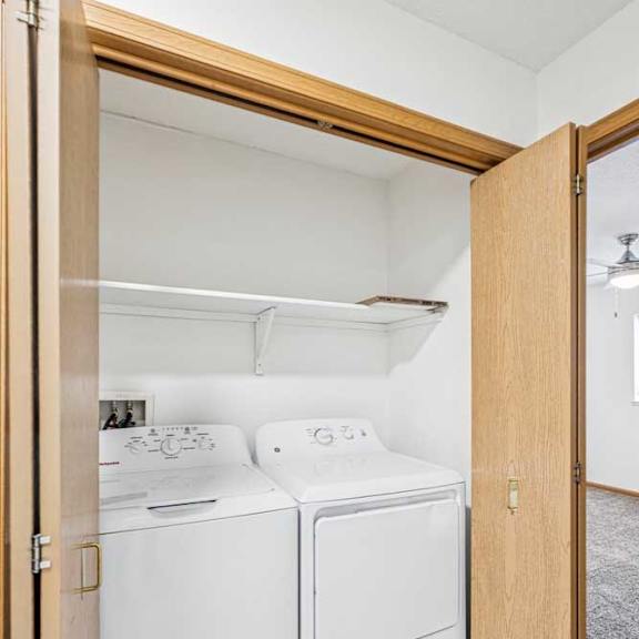 Thumbnail 8 of 18 An in-unit, full-sized washer and dryer in a laundry closet with overhead storage.