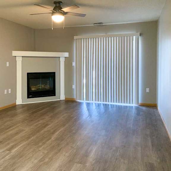 Thumbnail 7 of 21 a living room with a fireplace and mantle, a ceiling fan, and vertical blinds