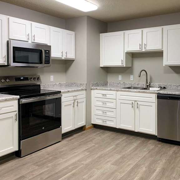 Thumbnail 4 of 21 a kitchen with white cabinets, stainless appliances, and hardwood floors