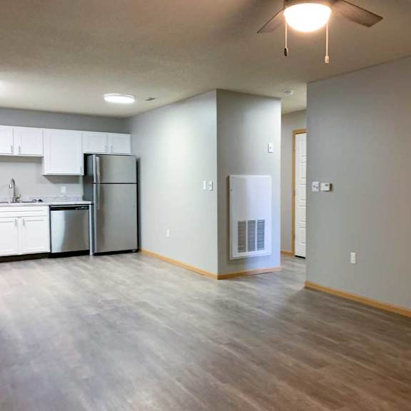 Thumbnail 12 of 21 a kitchen with white cabinets and stainless steel appliances and a large living room with hardwood flooring