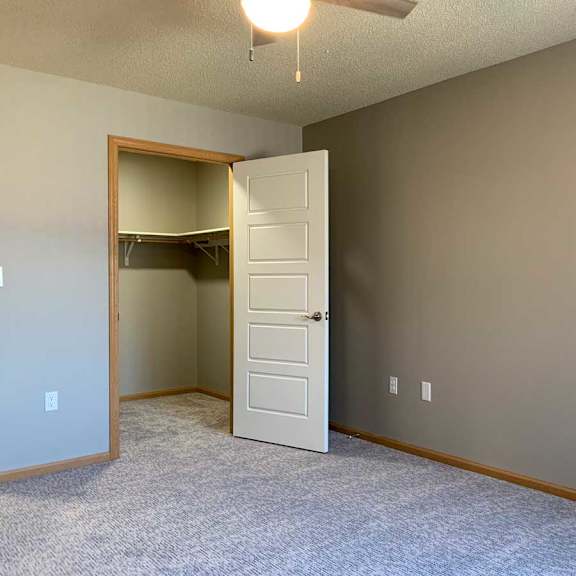 Thumbnail 16 of 21 a bedroom with a door to a walk-in closet and a ceiling fan