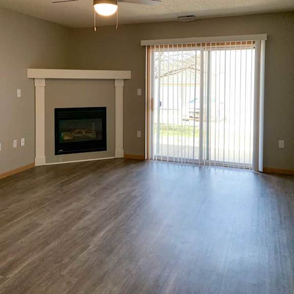 Thumbnail 8 of 21 a spacious living room with a fireplace, a mantle, a sliding glass door to the patio, and a ceiling fan