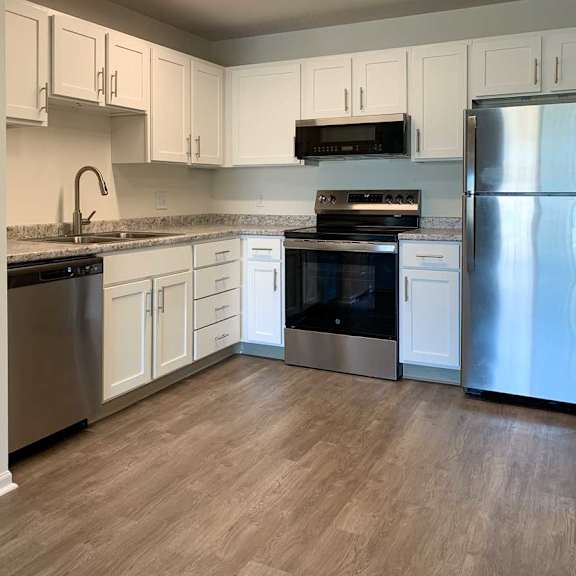 Thumbnail 9 of 16 an updated L-shape kitchen with white cabinets, stainless steel appliances, granite countertops, and hardwood flooring