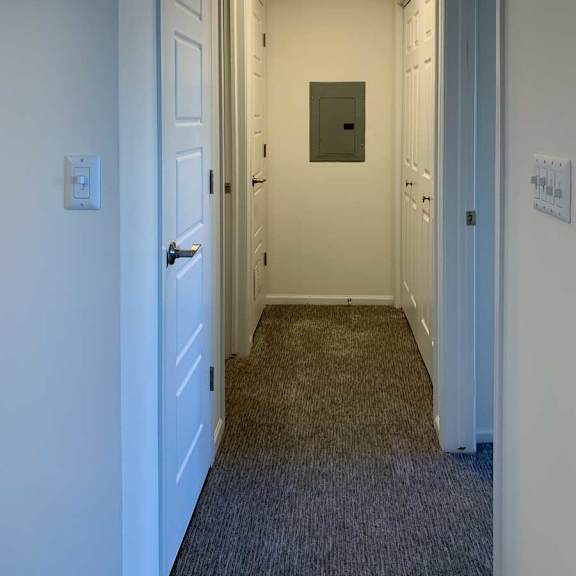 Thumbnail 12 of 16 a hallway with carpeted flooring and several closets on either side