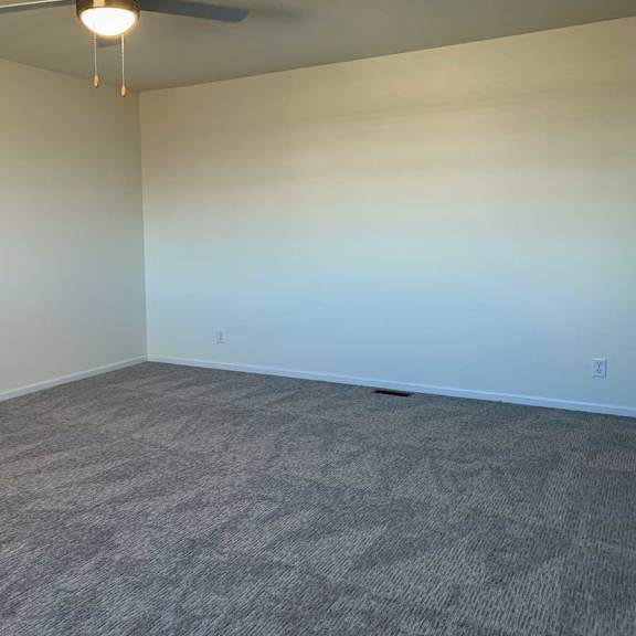 Thumbnail 16 of 16 a spacious bedroom with carpeted flooring and a ceiling fan