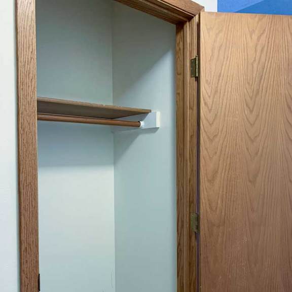 Thumbnail 12 of 30 a hallway coat closet with a built-in shelf and a wooden door