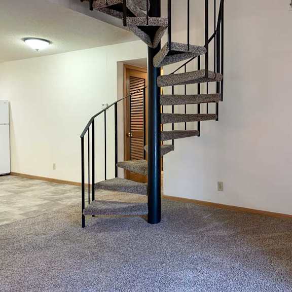 Thumbnail 6 of 30 a spiral staircase with a metal railing and a carpeted floor in a living room