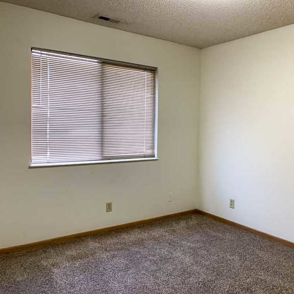 Thumbnail 15 of 30 a bedroom with white walls, carpeted flooring, and a window with blinds