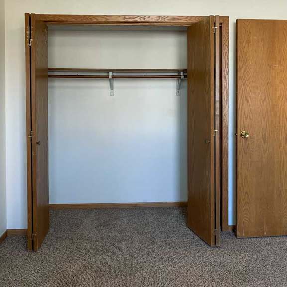 Thumbnail 14 of 30 a bedroom closet with a white wall and a wooden door
