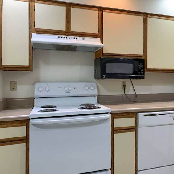 Thumbnail 4 of 30 a kitchen with a white stove and dishwasher, a mounted microwave, and white and wooden cabinets