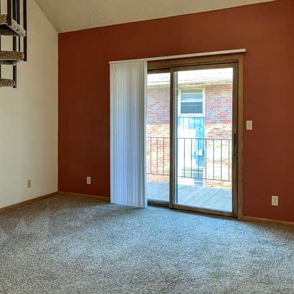 Thumbnail 7 of 30 a living room featuring a rust-colored accent wall with a sliding glass door and vertical blinds