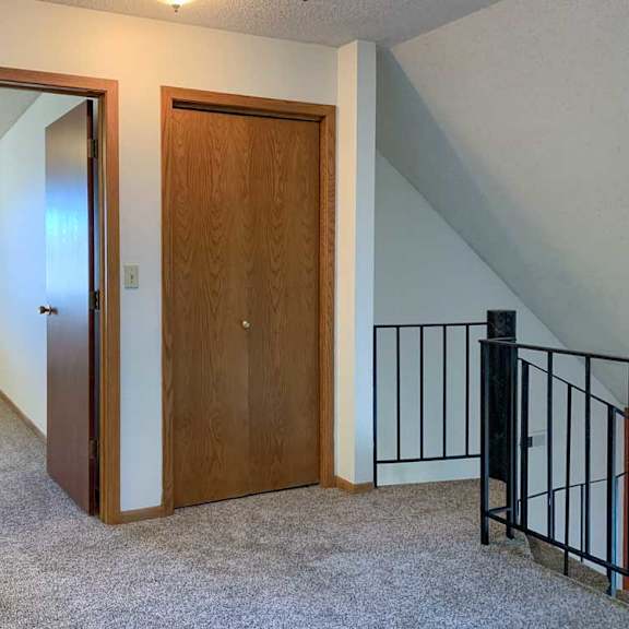 Thumbnail 23 of 30 a loft area with a metal railing, a closet storage closet, and a door open to a bedroom
