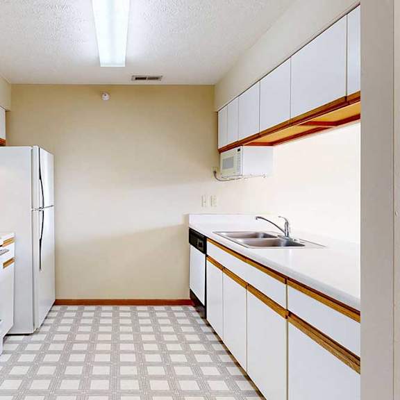 a galley kitchen with white cabinets with oak trim, white appliances, a double-basin sink, and a pass-through window countertop.