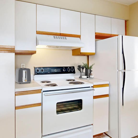Thumbnail 5 of 40 A white kitchen with a stove, oven, and refrigerator.