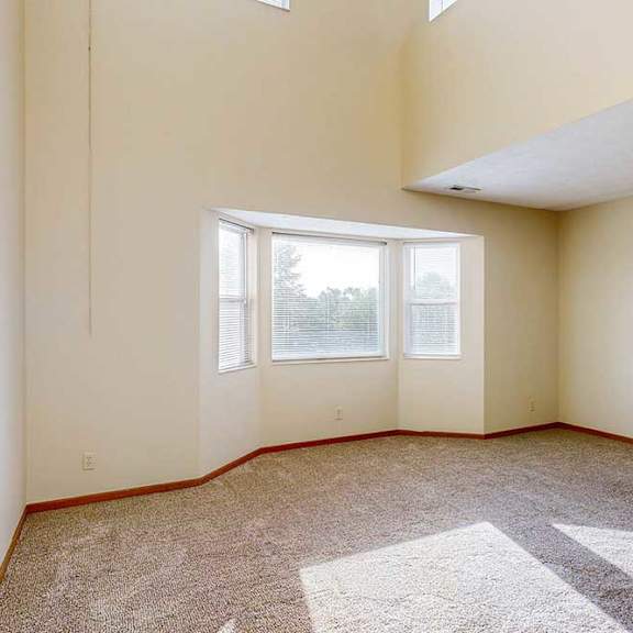 a carpeted living room with a bay window, and a two-story ceiling above.