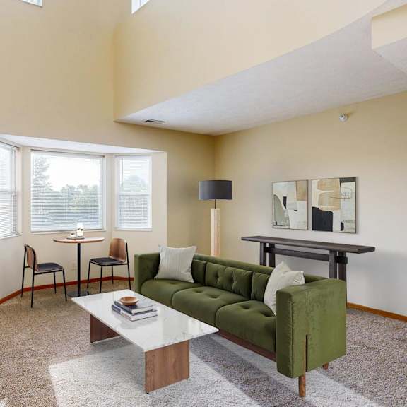 Thumbnail 15 of 40 A virtually staged apartment living room with a green couch and a coffee table.