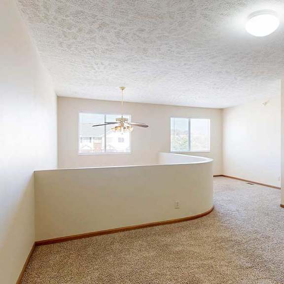 Thumbnail 31 of 33 A loft bedroom with two windows, a ceiling fan, and a opening to the living room below.