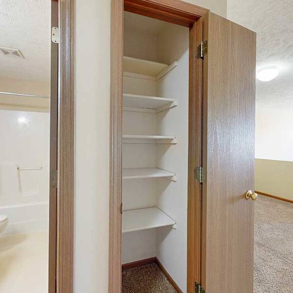 Thumbnail 30 of 33 A linen closet with built-in shelves, next to an open door to the bathroom.