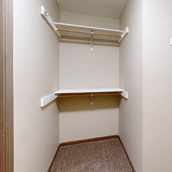Thumbnail 26 of 33 A spacious walk-in closet with three built-in shelves and hanging space.