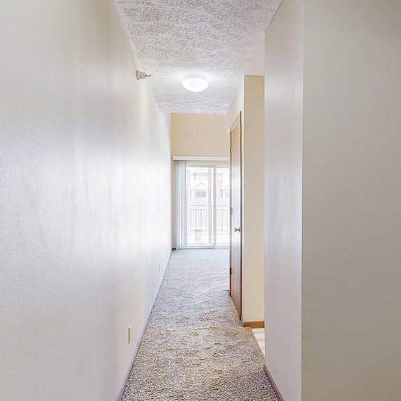 Thumbnail 2 of 33 A hallway with an alcove to the hallway bathroom, access to the kitchen, and the living room at the end.